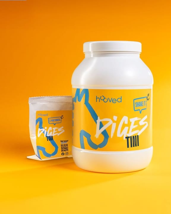 Weiße Proteinpulverdose und kleine Packung auf gelbem Hintergrund, beide mit blauer und gelber Verpackung, beschriftet mit "BICES TINI" und "shake it".